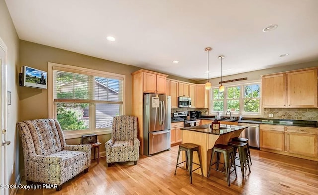 kitchen featuring stainless steel appliances, dark countertops, tasteful backsplash, light brown cabinetry, and a sink