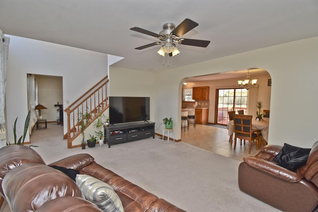living area with carpet flooring, stairway, baseboards, arched walkways, and ceiling fan with notable chandelier