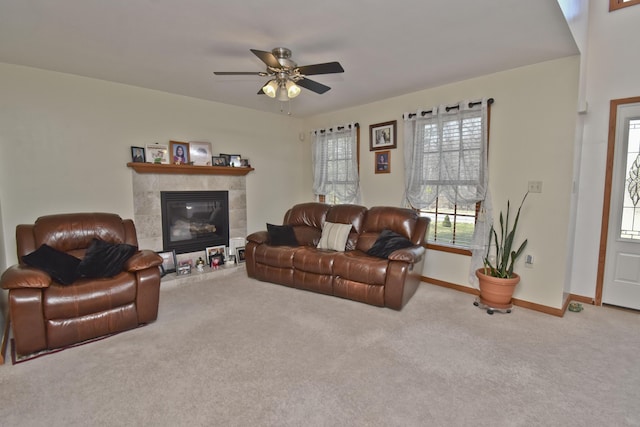 living area with a tiled fireplace, baseboards, ceiling fan, and carpet