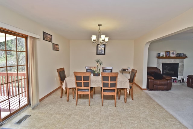 dining area featuring arched walkways, an inviting chandelier, a tile fireplace, baseboards, and visible vents