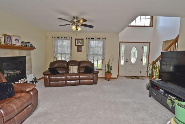 living room featuring baseboards, ceiling fan, a fireplace, and carpet flooring