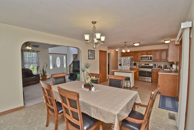 dining area featuring light tile patterned floors, arched walkways, visible vents, and ceiling fan with notable chandelier