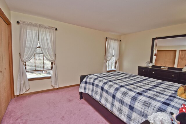 carpeted bedroom featuring baseboards and multiple windows
