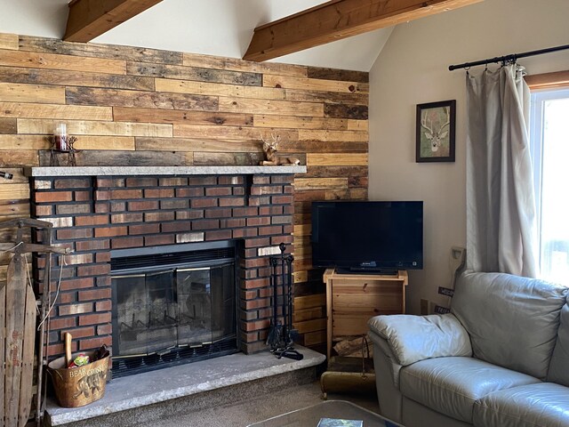 living area with wood walls, lofted ceiling with beams, and a fireplace