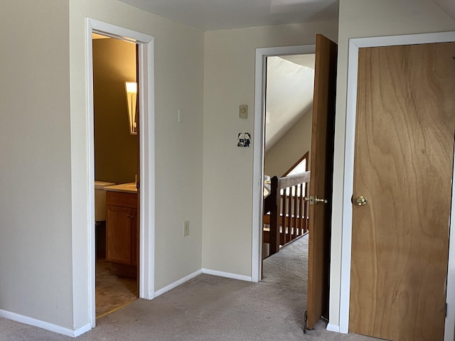 hall with an upstairs landing, carpet floors, and baseboards