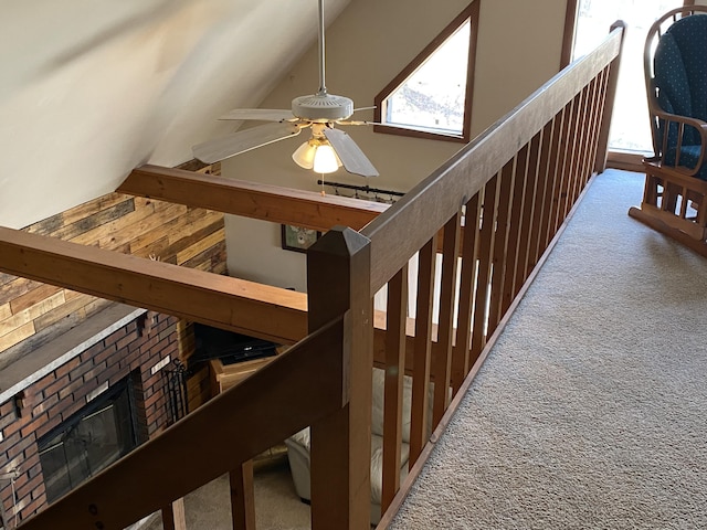 stairway featuring high vaulted ceiling, ceiling fan, carpet, and a fireplace