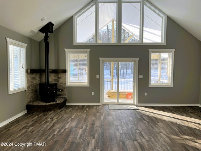 unfurnished living room with a wood stove, high vaulted ceiling, baseboards, and dark wood finished floors