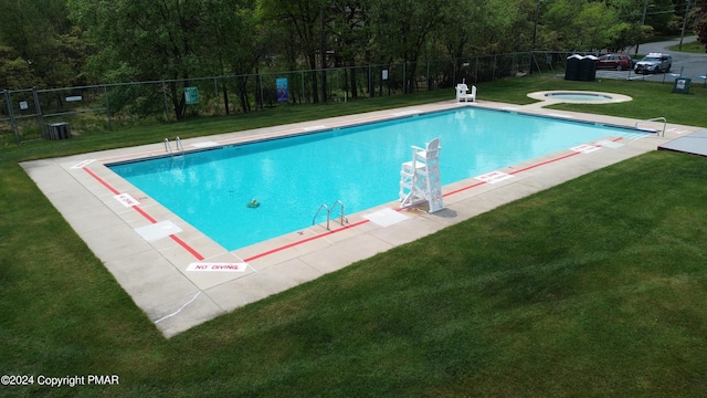 pool with a community hot tub, fence, central AC unit, and a lawn