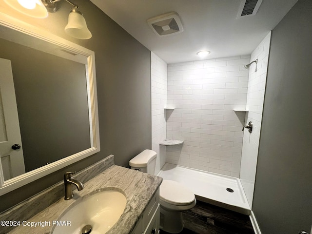 full bath featuring visible vents, tiled shower, vanity, and toilet