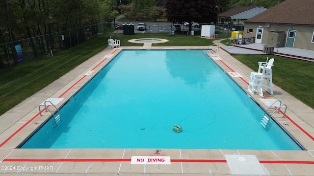 community pool featuring a community hot tub, fence, a patio, and a lawn