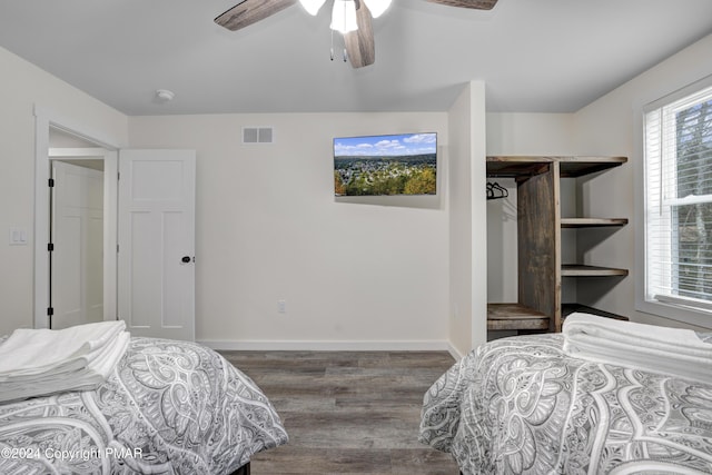 bedroom with a ceiling fan, visible vents, baseboards, and wood finished floors