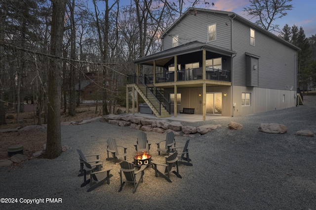 back of house at dusk featuring an outdoor fire pit, a patio, and stairway