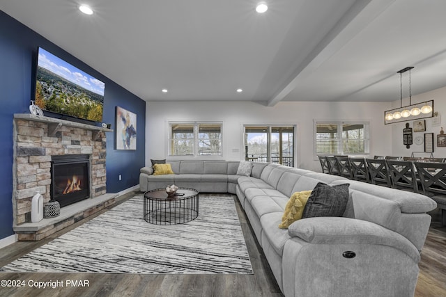 living area with baseboards, wood finished floors, and a stone fireplace