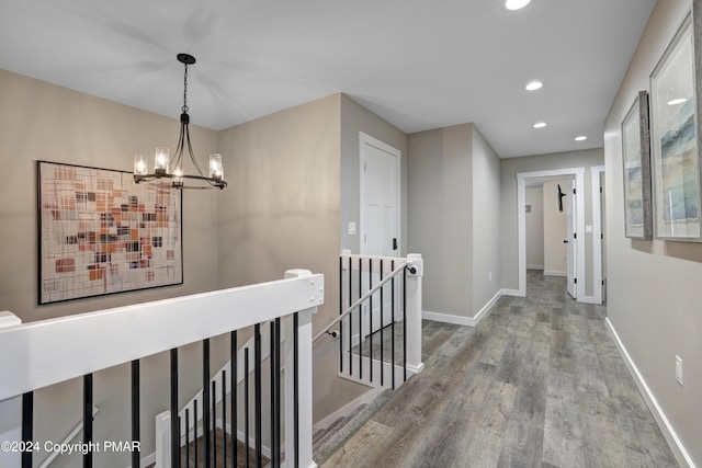 hallway with a notable chandelier, recessed lighting, wood finished floors, an upstairs landing, and baseboards