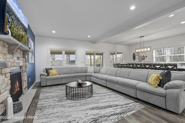 living area with plenty of natural light, a fireplace, beamed ceiling, and wood finished floors