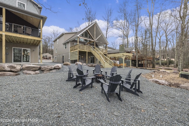 rear view of house with a fire pit, a wooden deck, and stairs