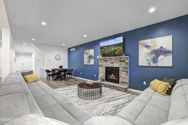 living area with baseboards, a stone fireplace, wood finished floors, and recessed lighting