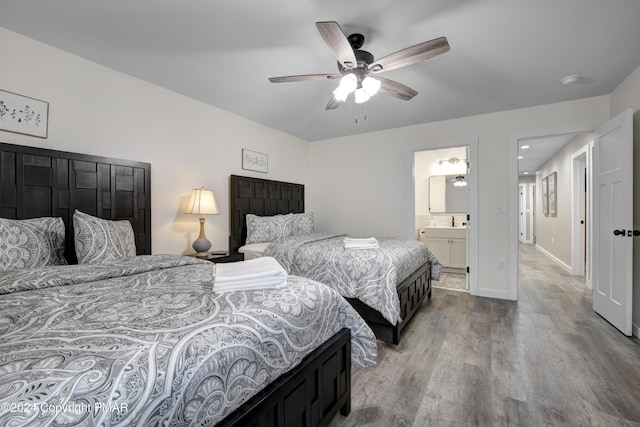 bedroom with a ceiling fan, a sink, ensuite bath, wood finished floors, and baseboards