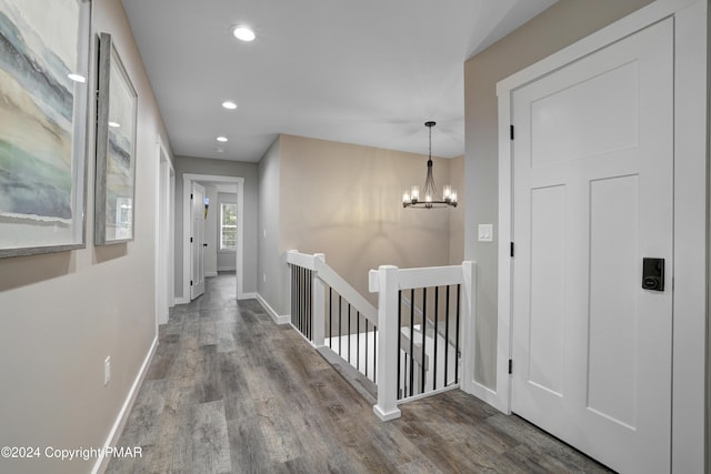 corridor featuring baseboards, wood finished floors, an inviting chandelier, an upstairs landing, and recessed lighting