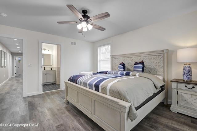 bedroom with ensuite bath, baseboards, visible vents, and dark wood-style flooring