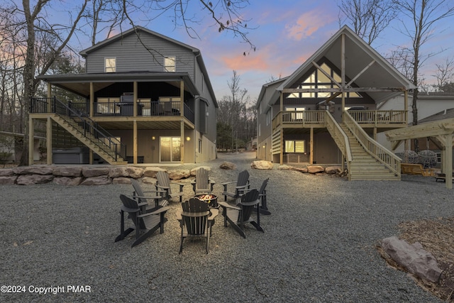 back of property at dusk featuring a fire pit, stairway, and a wooden deck