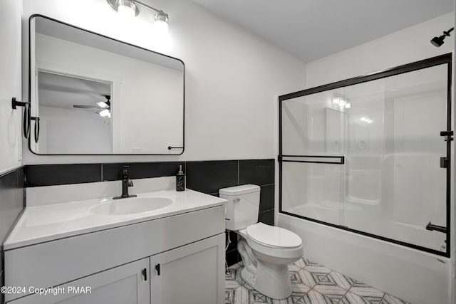 full bath featuring tile walls, toilet, a ceiling fan, enclosed tub / shower combo, and vanity