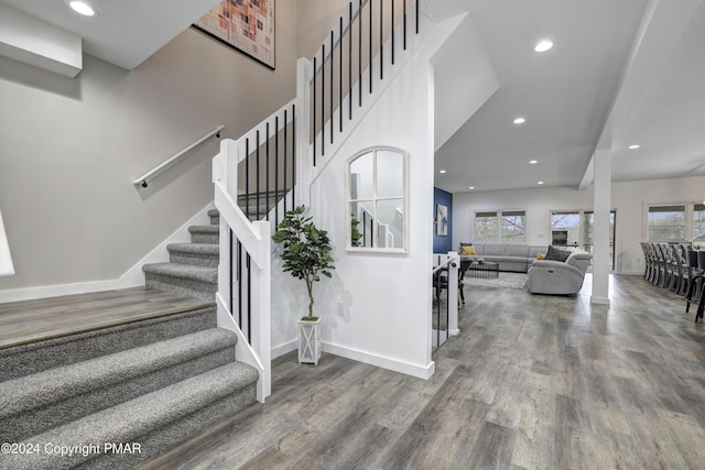 stairs with baseboards, recessed lighting, wood finished floors, and a healthy amount of sunlight