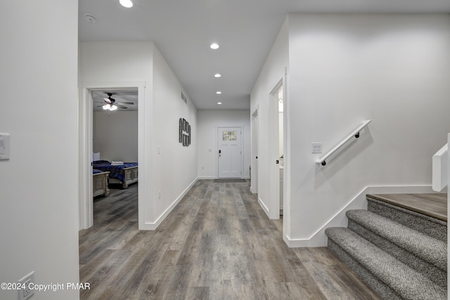 hallway with stairs, recessed lighting, baseboards, and wood finished floors