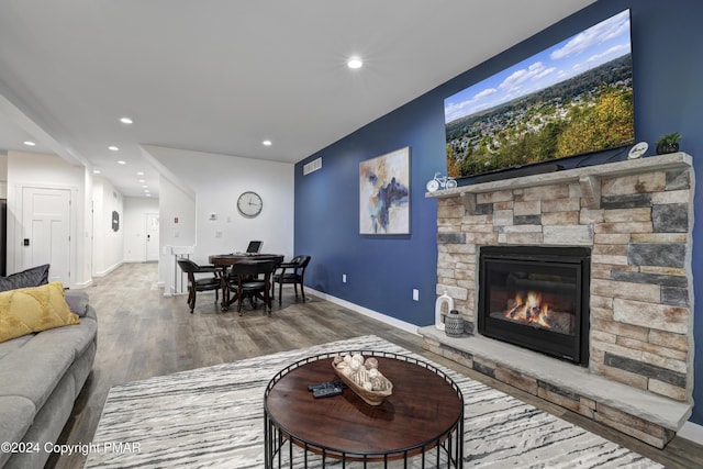 living room featuring a fireplace, recessed lighting, visible vents, wood finished floors, and baseboards