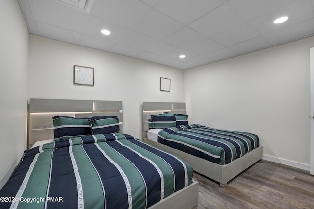 bedroom with recessed lighting, a drop ceiling, wood finished floors, and baseboards