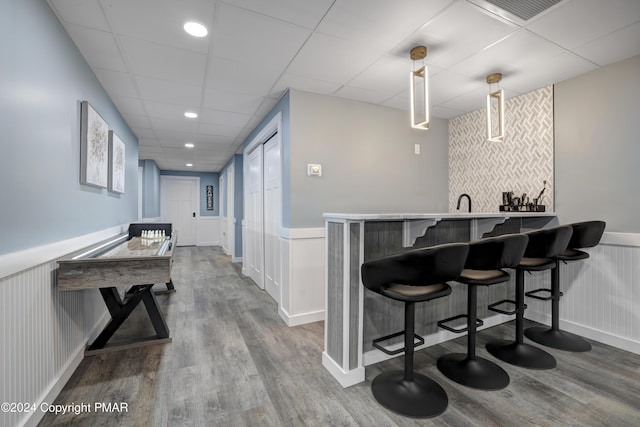 bar featuring a wainscoted wall, visible vents, indoor wet bar, and wood finished floors