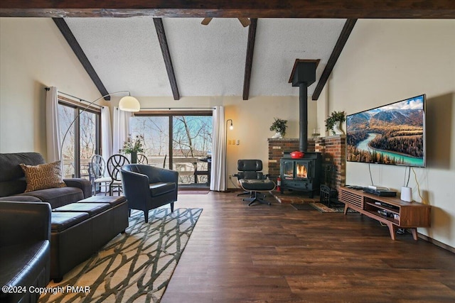 living area with beam ceiling, a wood stove, a textured ceiling, wood finished floors, and high vaulted ceiling