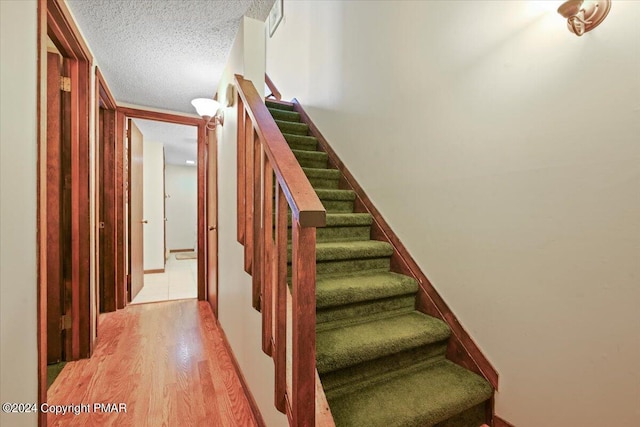 stairway featuring a textured ceiling and wood finished floors