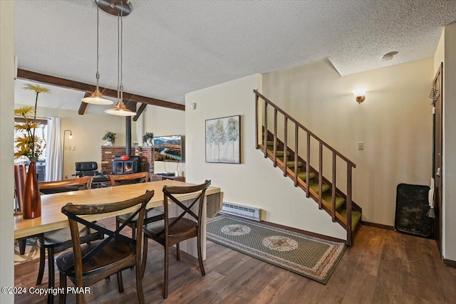 dining room featuring wood finished floors, beamed ceiling, a wood stove, stairs, and a textured ceiling