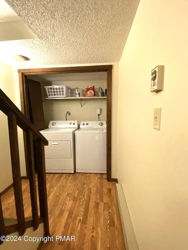 washroom with light wood finished floors, laundry area, separate washer and dryer, and a textured ceiling