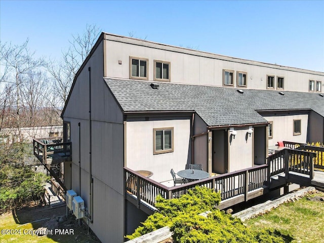 back of house featuring roof with shingles and a deck