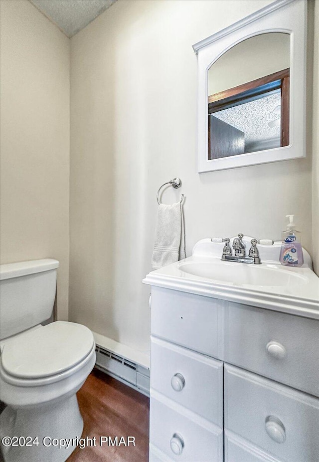 half bathroom featuring toilet, a baseboard radiator, and vanity