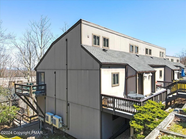 exterior space featuring a shingled roof and a wooden deck