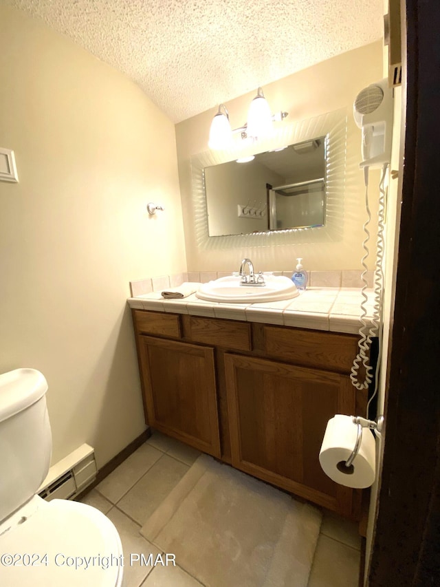 full bath featuring toilet, a baseboard heating unit, vanity, a textured ceiling, and tile patterned flooring