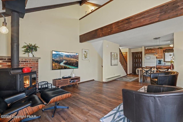 living room with beam ceiling, stairway, baseboard heating, a wood stove, and wood finished floors