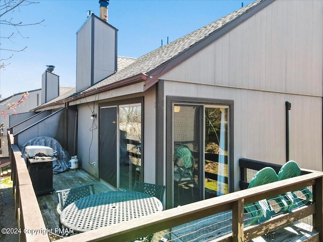 rear view of house featuring a shingled roof and a chimney