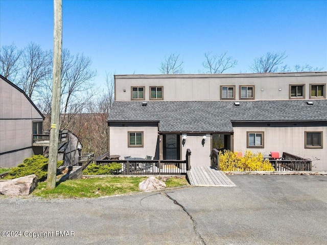 multi unit property with stucco siding and roof with shingles