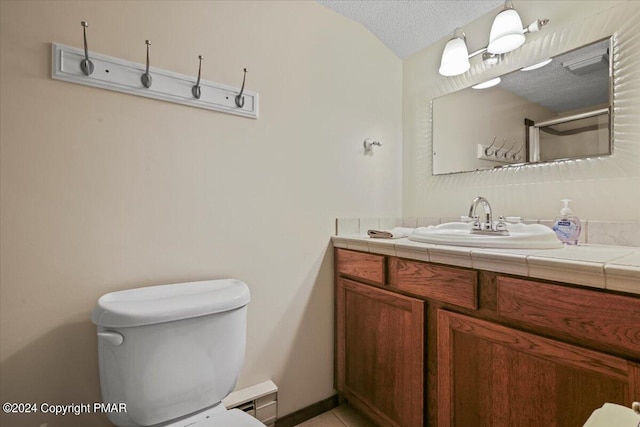 bathroom with a textured ceiling, toilet, vanity, vaulted ceiling, and walk in shower