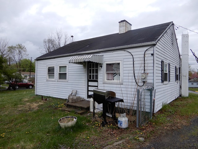 rear view of property featuring roof with shingles and a chimney