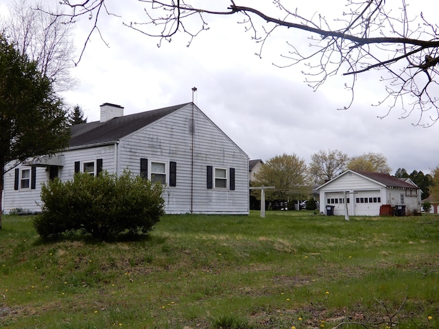 view of side of property with a chimney and a detached garage