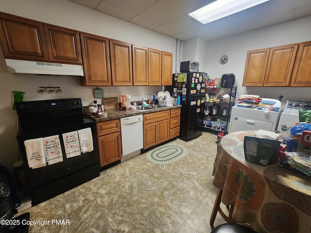 kitchen featuring a drop ceiling, under cabinet range hood, separate washer and dryer, brown cabinets, and black appliances