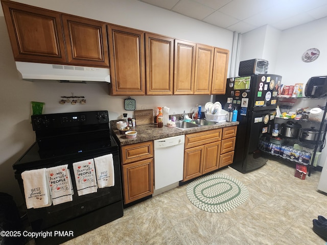 kitchen with a paneled ceiling, under cabinet range hood, a sink, brown cabinets, and black appliances