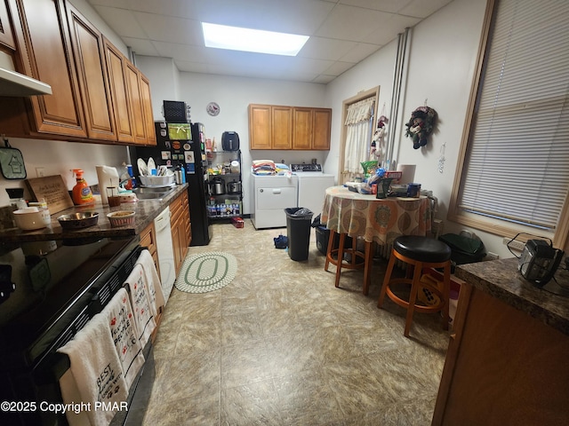 kitchen featuring dark countertops, brown cabinets, and washing machine and clothes dryer