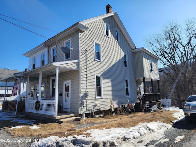 view of home's exterior with covered porch and a chimney