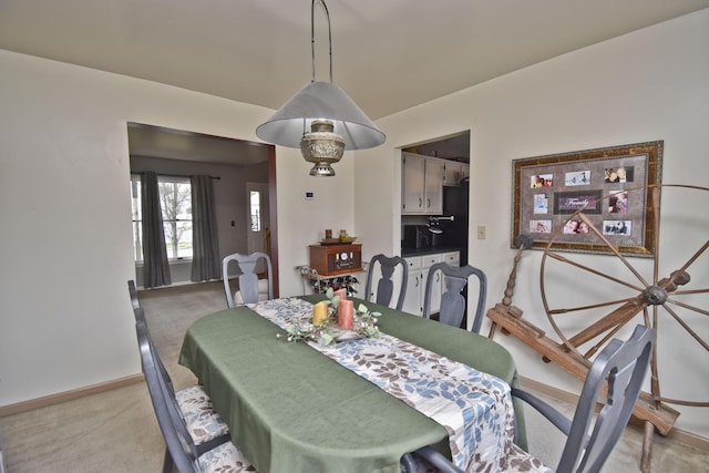 dining space featuring light colored carpet and baseboards